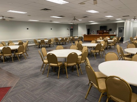 View of the banquet hall interior with overhead lights on, showing the bar.